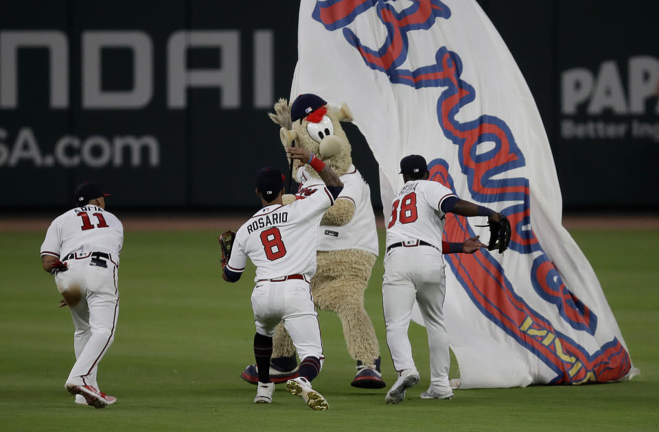 Atlanta Braves outfielders Orlando Arcia, Eddie Rosario (8) and Guillermo Heredia, from left, celebrate the team's 3-0 win over the Miami Marlins in a baseball game with team mascot Blooper, Friday, April 22, 2022, in Atlanta. (AP Photo/Ben Margot)