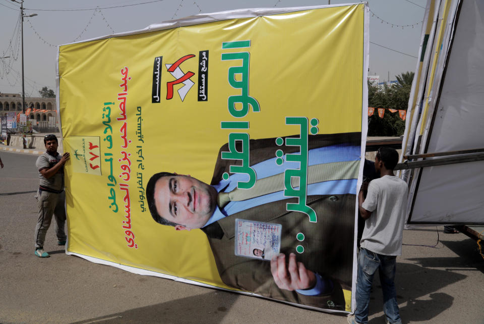 In this photo taken on April 7, 2014 workers prepare to place an election poster depicting candidate, Abdul Sahib Bzon, as he holds his national identity card, in Tahrir Square, Baghdad, Iraq. The vibrant posters promise jobs, prosperity and security coming from Iraq’s first parliamentary elections since U.S. troops withdrew from the country, but so far, voters have only dim hopes as sectarian bloodshed rages unstopped. (AP Photo/Khalid Mohammed)