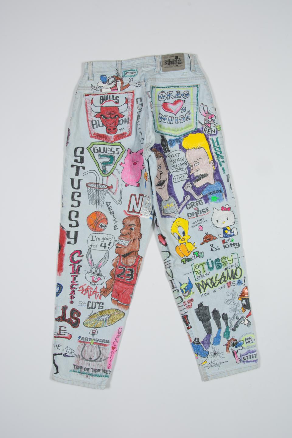Slver tab jeans with customer added modewrn iconography and cartoons including Chicago Bulls Bevis and Butthead Hello Kitty Tweety Stussy NBA Daffy Duck Taz Jurassic Park created by Ben Ramirez