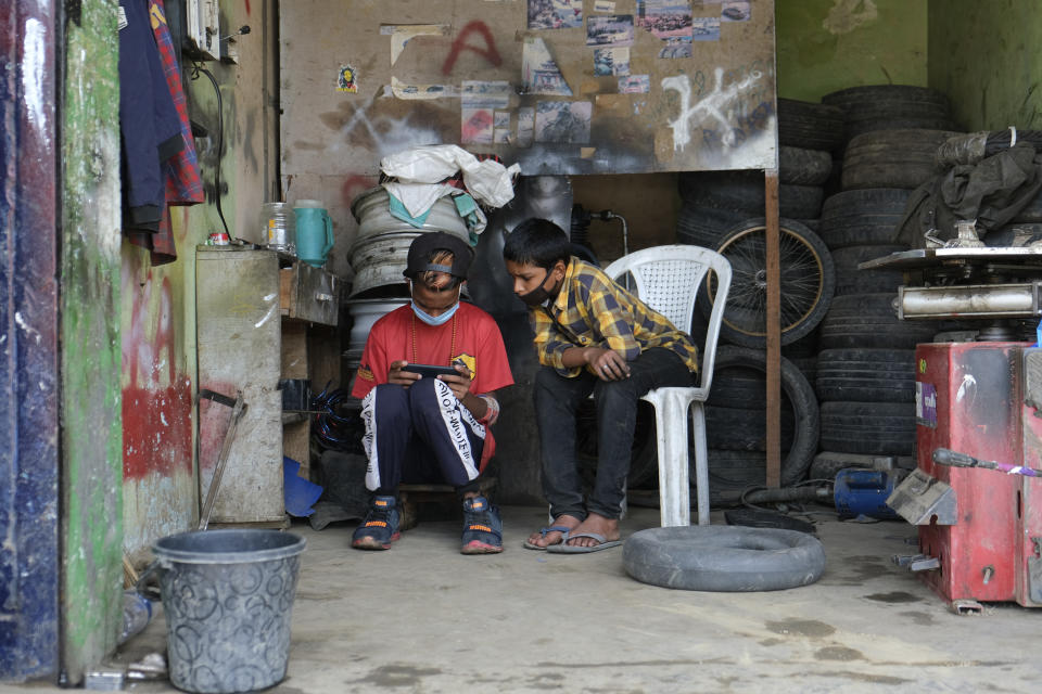 Boys wearing face masks take a break as they work at a tire repair shop in Kohima, capital of the northeastern Indian state of Nagaland, Friday, May 29, 2020. India’s economic growth will fall to 4.2% in financial year 2019-20 as compared to 6.1% in the previous year and likely to contract this year because of the coronavirus pandemic. Millions of workers have fled cities after losing their jobs as authorities imposed the lockdown in March and started easing it early this month to promote economic activity. (AP Photo/Yirmiyan Arthur)