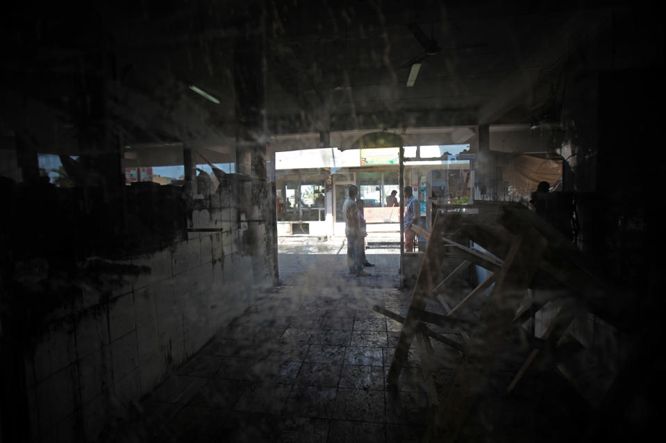 Asian workers are seen through glass after several shops and a market near the police station were damaged by people hurling petrol bombs in Sitra, Bahrain, Tuesday, May 6, 2014. Bahraini police have confronted attackers who tried to firebomb a police post in a largely Shiite community in the tiny Gulf island nation, authorities said Tuesday. (AP Photo/Hasan Jamali)