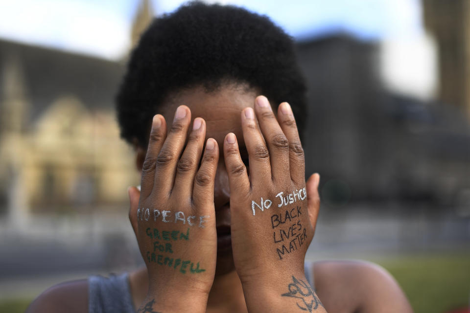 FILE - In this file photo dated Sunday, June 21, 2020, a woman symbolically covers her eyes as she participates in a Black Lives Matter protest calling for an end to racial injustice, at the Parliament Square in central London. A government inquiry, by a panel of experts, has concluded Wednesday March 31, 2021, that there is racism in Britain, but it’s not a systematically racist country that is “rigged” against non-white people, though many ethnic-minority Britons greeted that claim with skepticism. (AP Photo/Alberto Pezzali)