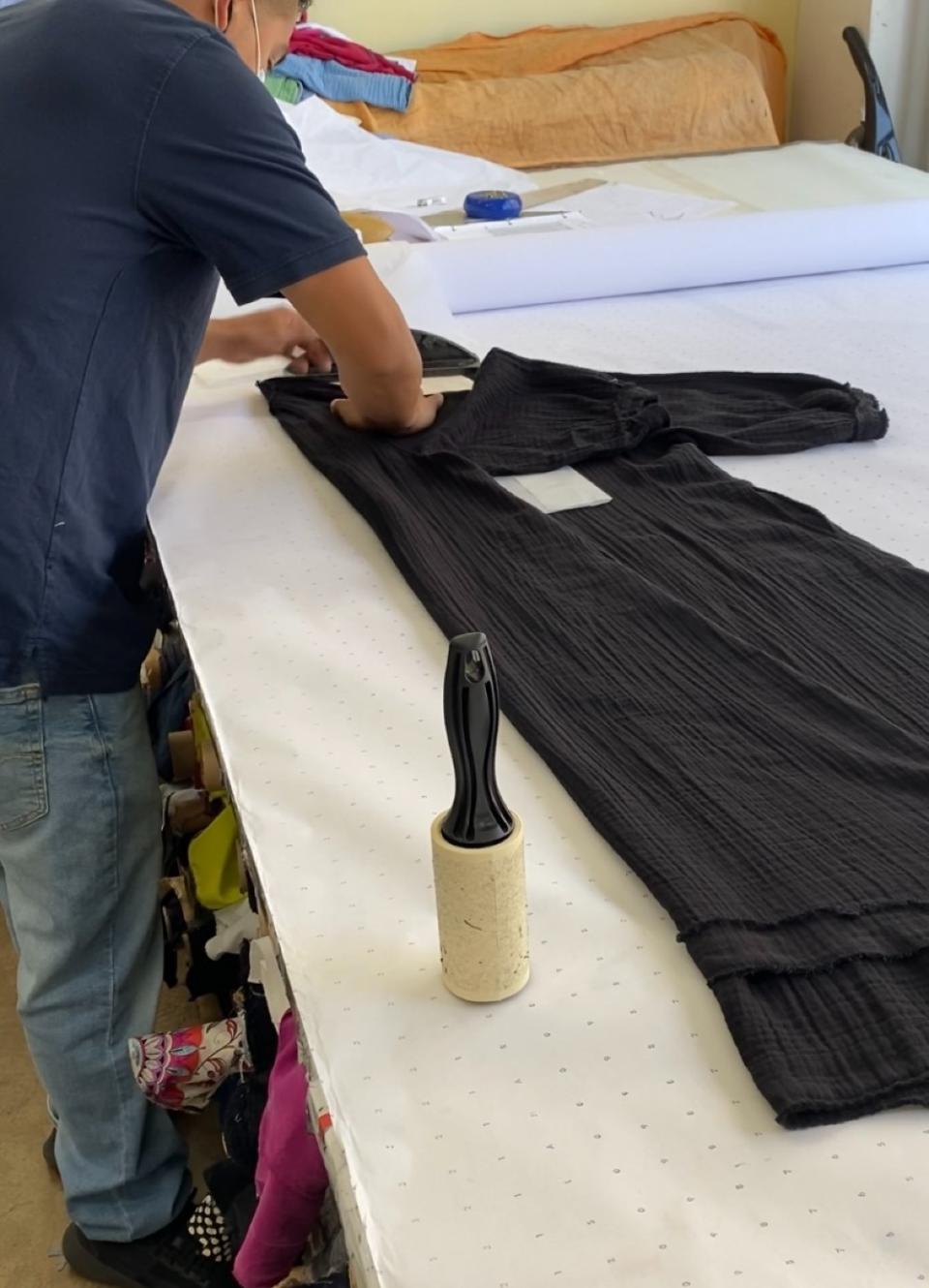 A worker at Ocean+Main putting the finishing touches on a caftan.