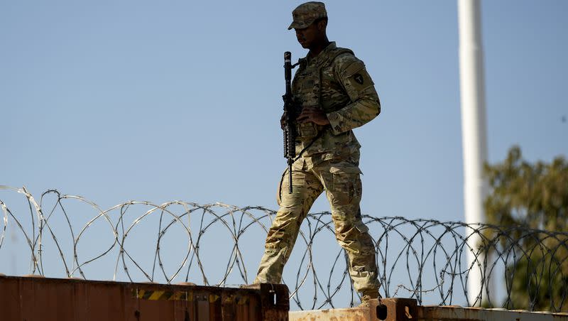 A guardsman walks over rail cars with Concertina wire along the Texas-Mexico border, Jan. 3, 2024, in Eagle Pass, Texas. 