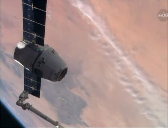 A SpaceX-built Dragon cargo ship floats near the end of the International Space Station's robotic arm, with the Earth as a backdrop, in this view from a station camera captured on April 20, 2014. The Dragon cargo ship delivered nearly 5,000 lbs