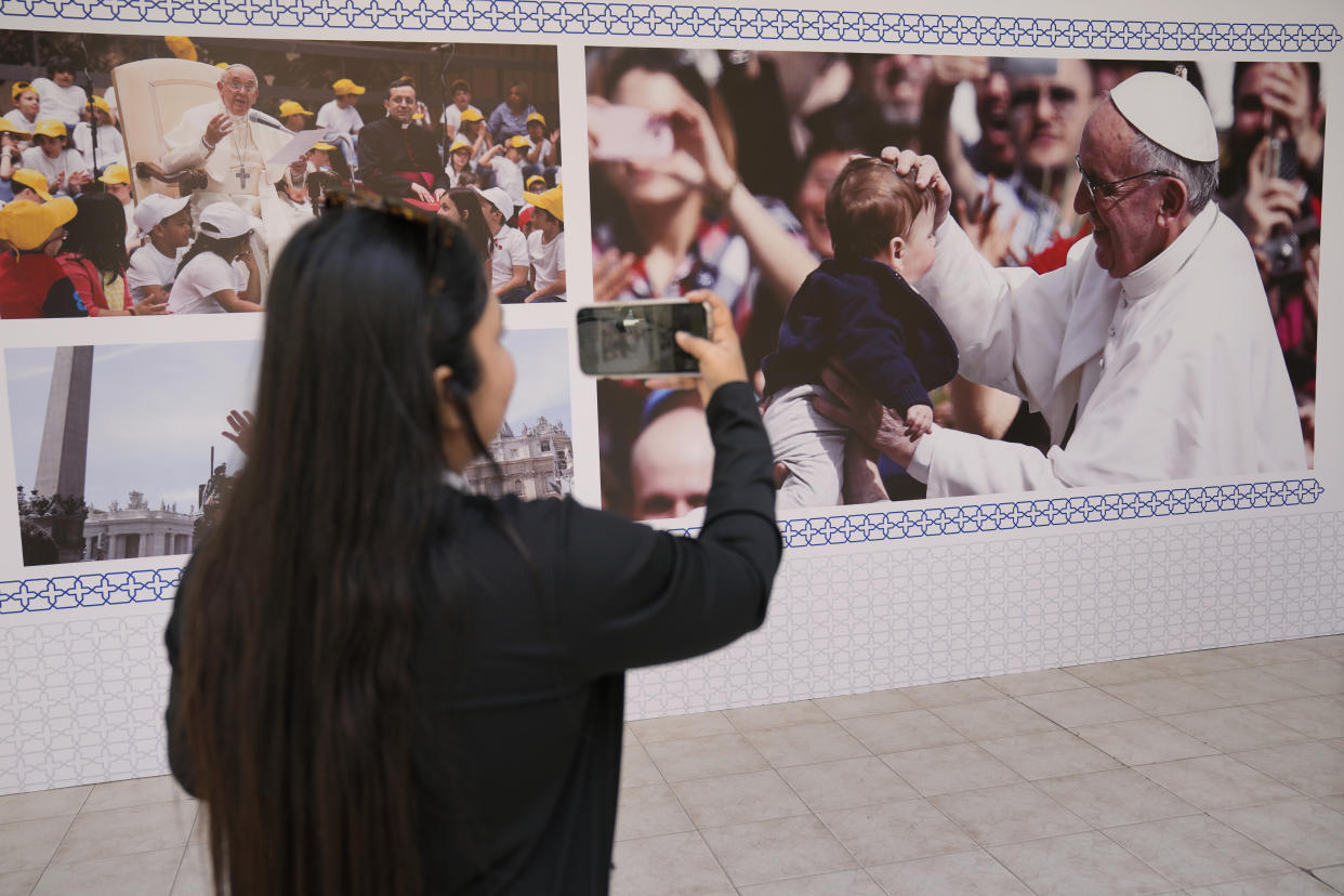 A woman takes pictures by her mobile phone for Pope Francis posters, outside the Sacred Heart church, in Manama, Bahrain, Wednesday, Nov. 2, 2022. Pope Francis is making the Nov. 3-6 visit to participate in a government-sponsored conference on East-West dialogue and to minister to Bahrain's tiny Catholic community, part of his effort to pursue dialogue with the Muslim world. (AP Photo/Hussein Malla)