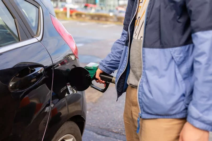 Man's hand holding petrol pump and filling car close up