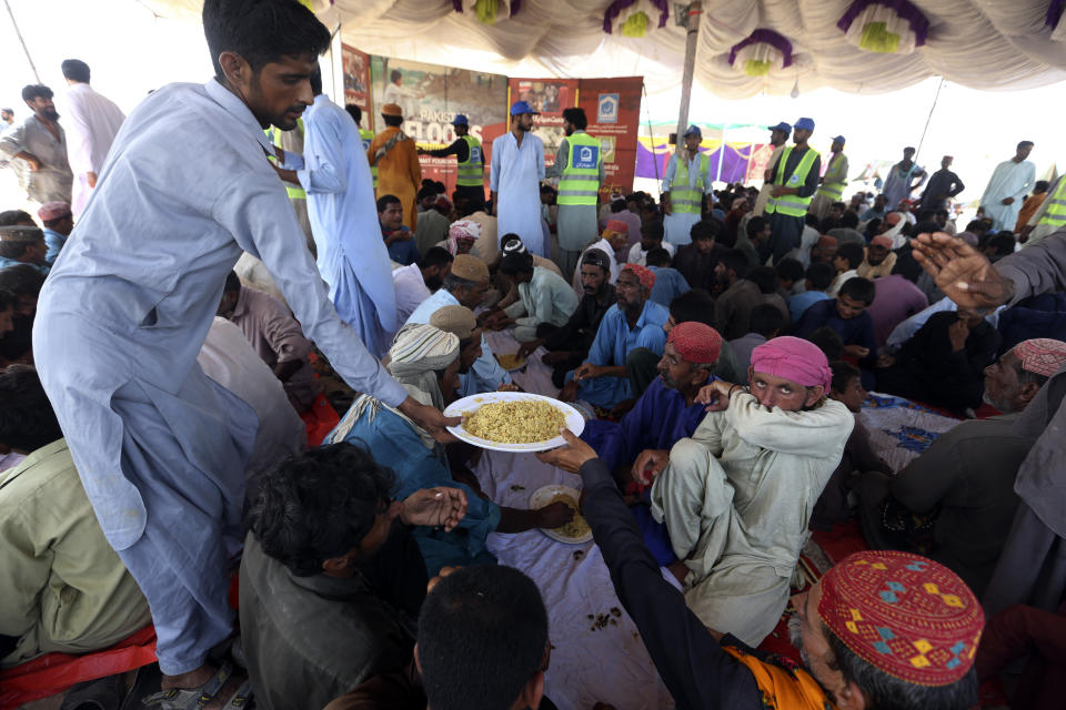 Victims of the unprecedented flooding from monsoon rains receive relief food organized by the Alkhidmat Foundation, in Jaffarabad, a district of Pakistan's southwestern Baluchistan province, Monday, Sept. 5, 2022. The U.N. refugee agency rushed in more desperately needed aid Monday to flood-stricken Pakistan as the nation's prime minister traveled to the south where rising waters of Lake Manchar pose a new threat. (AP Photo/Fareed Khan)