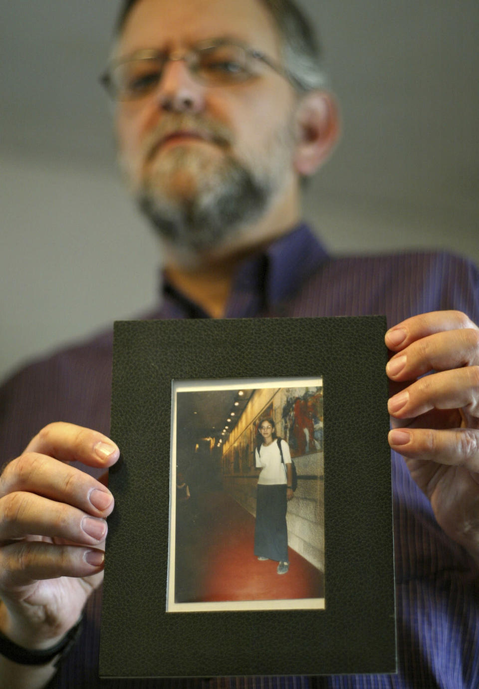 FILE - Arnold Roth holds a photo of his 15-year-old daughter Malki, who was killed in an August 2001 Palestinian suicide bombing at a Jerusalem pizzeria, at his house in Jerusalem, on Sept. 28, 2004. The family of an Israel-American girl killed in a 2001 Palestinian suicide bombing in Jerusalem is seeking a meeting with President Joe Biden in hopes of forcing Jordan to extradite Tamimi, who was convicted in the deadly attack. The parents of Malki Roth sent a letter to the White House on Sunday, July 10, 2022 asking to meet with Biden when he comes to Jerusalem this week. They want the president to put pressure on Jordan, a close American ally, to send Tamimi to the U.S. for trial. (AP Photo/Oded Balilty)