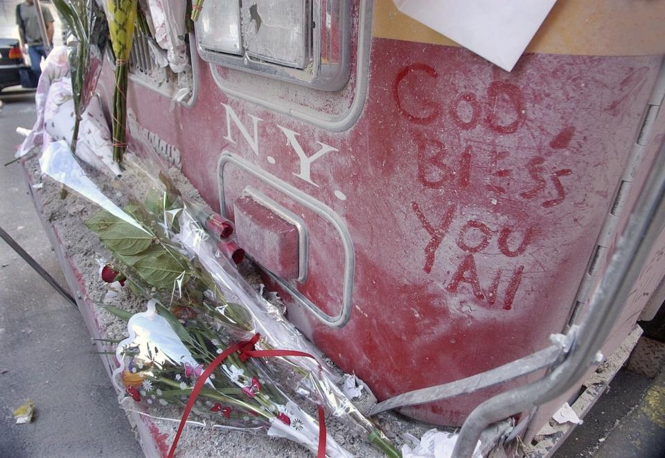 FILE - In this Wednesday, Sept. 12, 2001 file photo, flowers and messages written on the dust-coated ladder truck of Ladder Company 24 are seen a day after the terrorist attack on the World Trade Center in New York. Ladder Company 24 lost 7 firemen in the attack, including Fire Chaplain Father Mychal Judge. (AP Photo/Amy Sancetta, File)