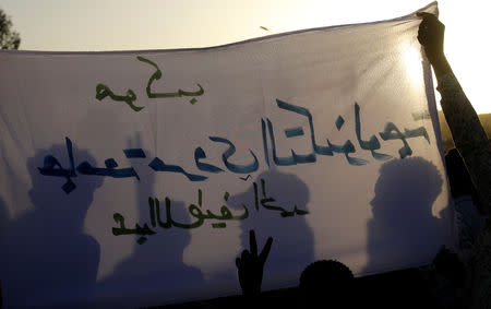 Shadow of Sudanese protesters cast on a banner as they gather for a mass protest in front of the Defence Ministry in Khartoum, Sudan, April 21, 2019. REUTERS/Umit Bektas