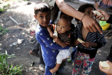 Venezuelan children receive bread by a man at a bus terminal, after being expelled from the Pacaraima border control point by civilians in Brazil, in Santa Elena, Venezuela August 19, 2018. REUTERS/Nacho Doce