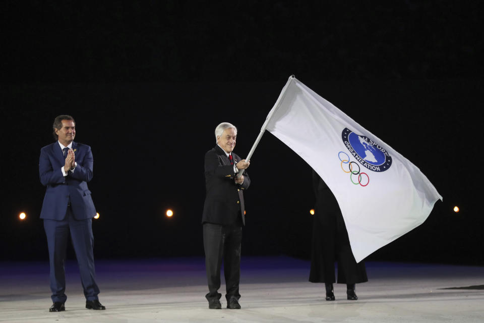 Chile's President Sebastian Pinera waves the Panam Sports flag during the closing ceremony of the Pan American Games at the National stadium in Lima, Peru, Sunday, Aug. 11, 2019. Chile's capital Santiago will host the event in 2023. (AP Photo/Fernando Llano)