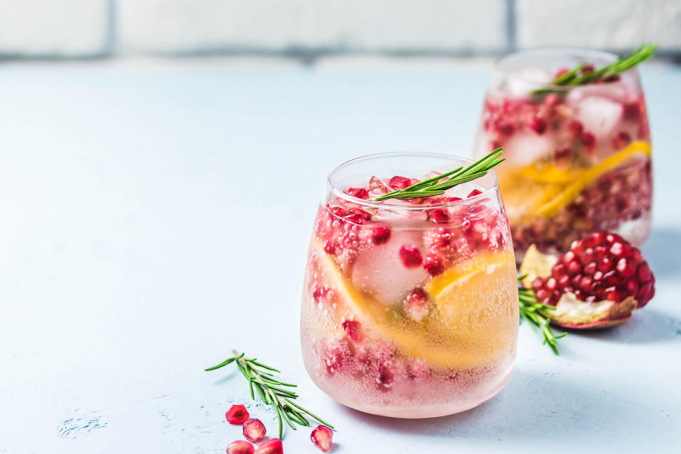 Two pomegranate cocktails with orange and rosemary