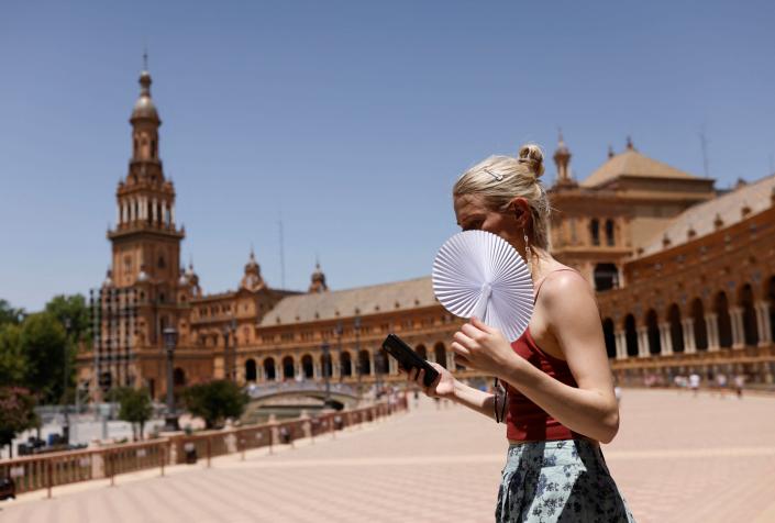 A woman fans herself during the first heatwave of the year in Seville, Spain (Marcelo del Pozo/Reuters)