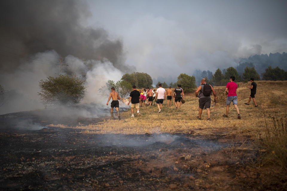 BARCELONA, CATALONIA, SPAIN - JULY 17: Neighbors collaborate in the work of extinction in a forest fire, on 17 July, 2022 seen from Sant Fruitos del Bages, Barcelona, Catalonia, Spain. The fire has started today Sunday at noon and already affects 95 hectares, in its extinction work 81 teams of the Bombers de la Generalitat, of which 13 are aerial. The fire, fanned by the south wind, advances 