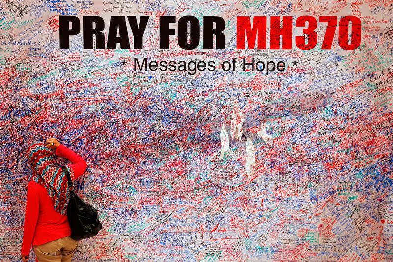 FILE PHOTO: A woman leaves message of support and hope for passengers of missing Malaysia Airlines MH370 in central Kuala Lumpur