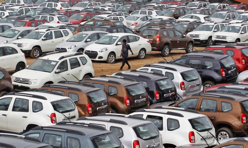 FILE PHOTO: A worker walks past parked Renault cars at its stockyard on the outskirts of Ahmedabad