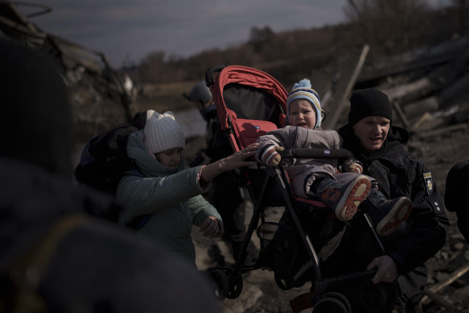 FILE A child is carried on a stroller across an improvised path while fleeing Irpin, on the outskirts of Kyiv, Ukraine, Wednesday, March 9, 2022. Quantifying the toll of Russia’s war in Ukraine remains an elusive goal a year into the conflict. Estimates of the casualties, refugees and economic fallout from the war produce an complete picture of the deaths and suffering. Precise figures may never emerge for some of the categories international organizations are attempting to track. (AP Photo/Felipe Dana, FIle)