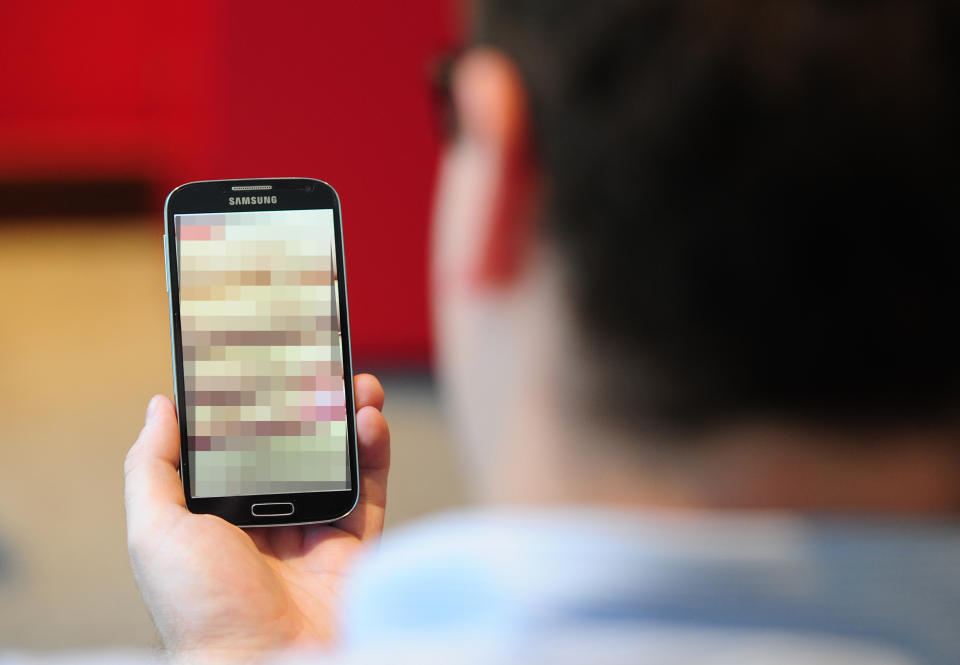 EMBARGOED TO 1030 MONDAY JULY 6 PICTURE POSED BY MODEL Undated photo of a man looking at a mobile phone. Threats to post revenge porn should be a crime, a charity said as it revealed one in seven young women have been threatened that their intimate photos will be shared without their consent.