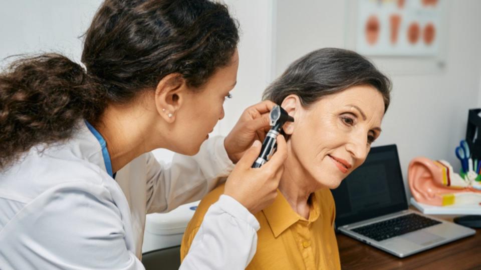 mature woman getting a health screening test for hearing by a female doctor in a medical office