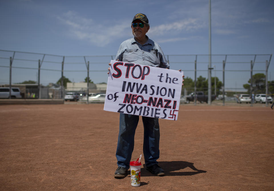 Gilberto Zuniga holds a sign to protest the visit of President Donald Trump to the border city after the Aug. 3 mass shooting in El Paso, Texas, Wednesday, Aug. 7, 2019. Trump headed to El Paso, after visiting Dayton, Ohio on Wednesday to offer a message of healing and unity, but he will be met by unusual hostility in both places by people who fault his own incendiary words as a contributing cause to the mass shootings. (AP Photo/Andres Leighton)