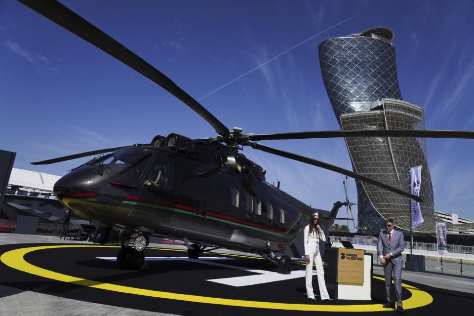 Russian salespeople stand by a helicopter made by Russian Helicopters at the International Defense Exhibition and Conference in Abu Dhabi, United Arab Emirates, Monday, Feb. 20, 2023. Just outside of Abu Dhabi's biennial arms fair in a large tent, Russia offered weapons for sale Monday ranging from Kalashnikov assault rifles to missile systems despite facing sanctions from the West over its war on Ukraine. (AP Photo/Jon Gambrell)