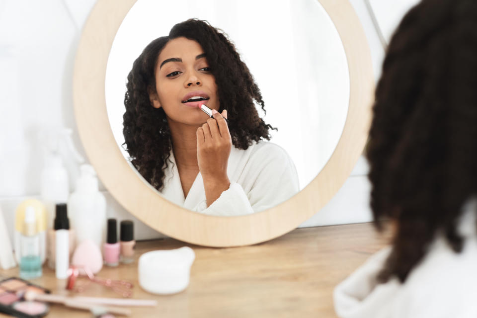 A woman doing her makeup in front of a mirror