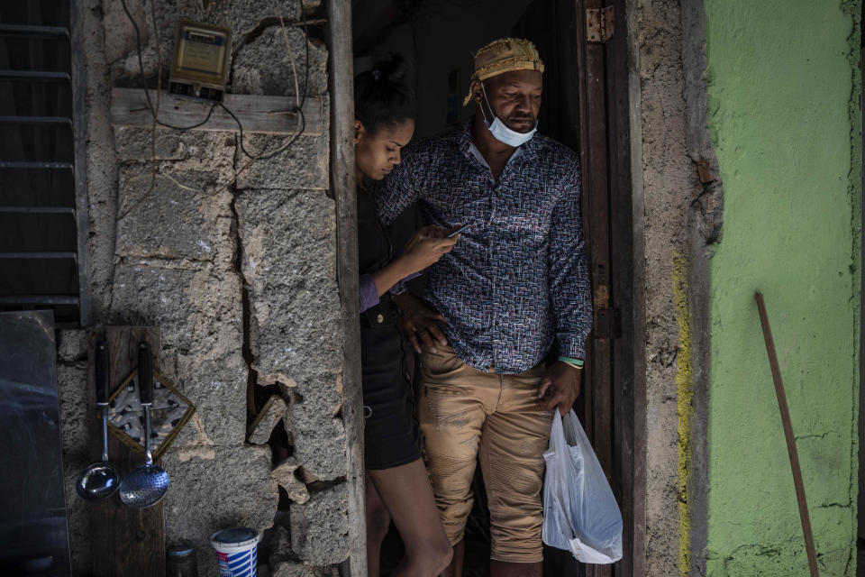 Emilio Román, right, father of two young men and a daughter who are in prison accused of participating in the recent protests against the government, poses with his daughter-in-law María Carla Milan Ramos at their home in the La Guinera neighborhood of Havana, Cuba, Wednesday, Jan. 19, 2022. Six months after surprising protests against the Cuban government, more than 50 protesters who have been charged with sedition are headed to trial and could face sentences of up to 30 years in prison. (AP Photo/Ramon Espinosa)