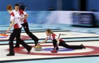 Canada's vice Kaitlyn Lawes (R) delivers a stone as lead Dawn McEwen (L) and second Jill Officer run ahead to sweep during their women's gold medal curling game against Sweden at the Ice Cube Curling Centre during the Sochi 2014 Winter Olympics February 20, 2014. REUTERS/Marko Djurica