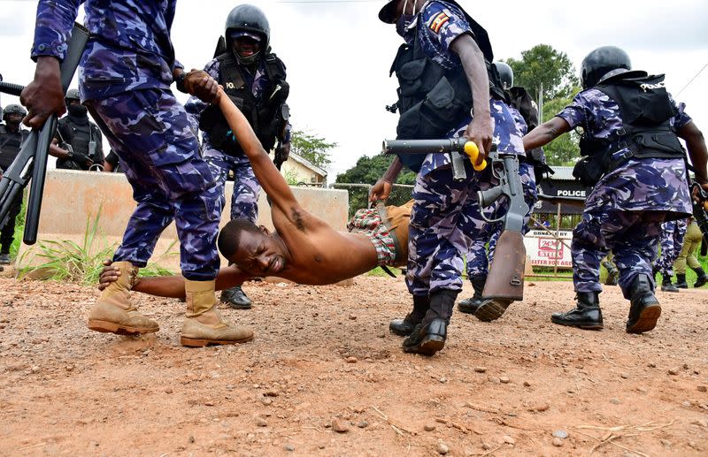 FILE PHOTO: Ugandan riot policemen detain a supporter of presidential candidate Robert Kyagulanyi, in Luuka district