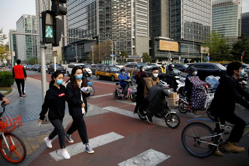 FILE PHOTO: People wearing face masks walk across a street at Beijing's Financial Street during evening rush hour, as the country is hit by an outbreak of the novel coronavirus disease (COVID-19)