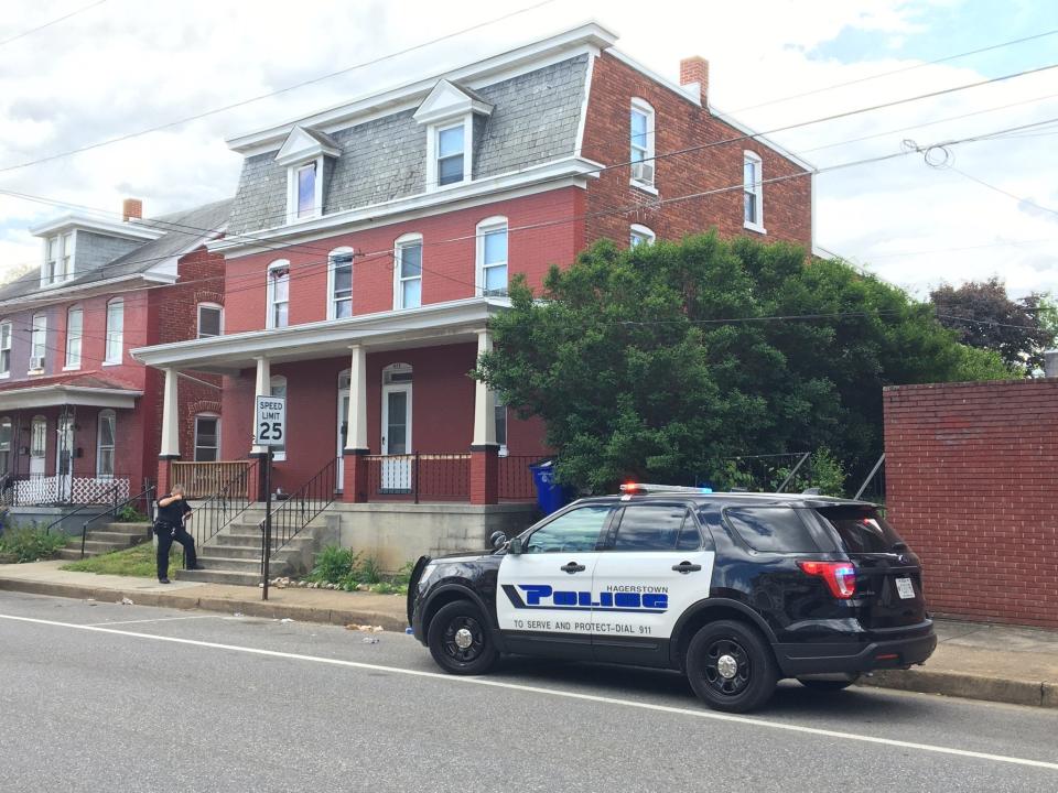 A Hagerstown Police Department SUV sits parked the afternoon of Friday, May 14, 2021, while an officer stands on the steps of the house in the 800 block of Washington Avenue. Police responded to an incident in the alley behind the house around noon.