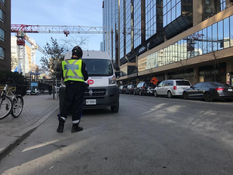 A Toronto police parking enforcement officer issues a ticket on Edward Street, north of Yonge-Dundas Square.