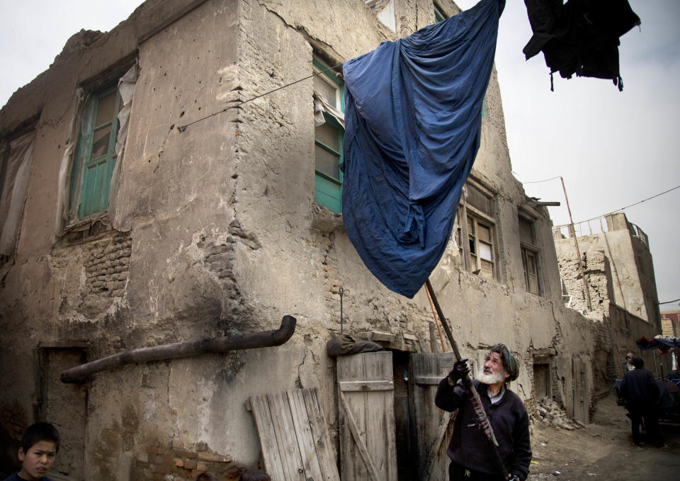 Haji Hussain, 75, who colors clothing for 40 years, takes a freshly colored burqa out for drying outside his small shop in the old town of Kabul, Afghanistan, Monday, April 15, 2013. Despite advances in women’s rights, Afghanistan remains a deeply conservative country and most women continue to wear the Burqa. But tradesmen say times are changing in Kabul at least, with demand for burqas declining as young women going to school and taking office jobs refuse to wear the cumbersome garments. (AP Photo/Anja Niedringhaus)