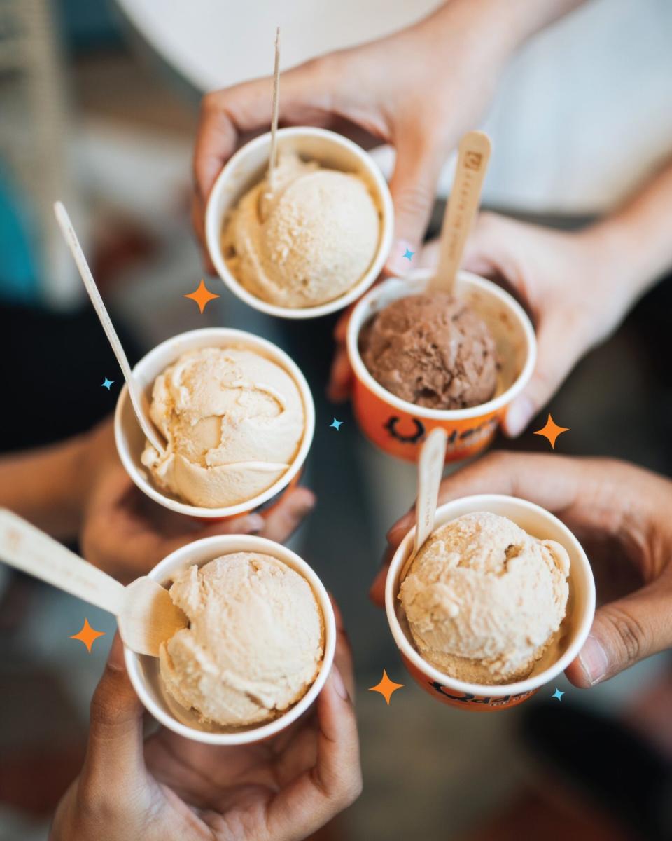 Udders Ice Cream - 5 hands holding cups of ice cream