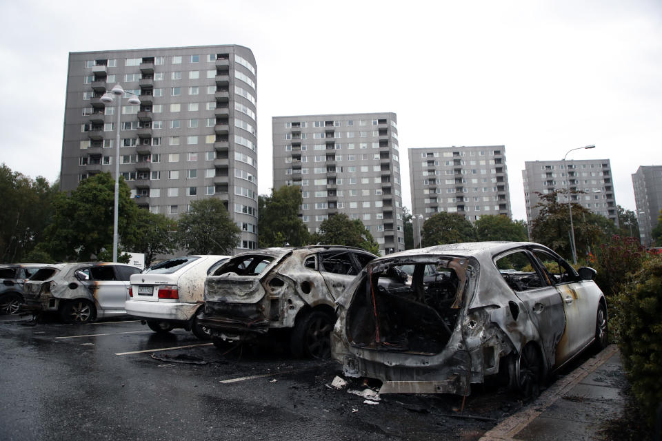 Burned cars parked at Frolunda Square in Gothenburg, Tuesday, Aug. 14, 2018. Masked youth torched dozens of cars overnight in Sweden and threw rocks at police, prompting an angry response from the prime minister, who on Tuesday spoke of an "extremely organized" night of vandalism. (Adam Ihse/TT via AP)