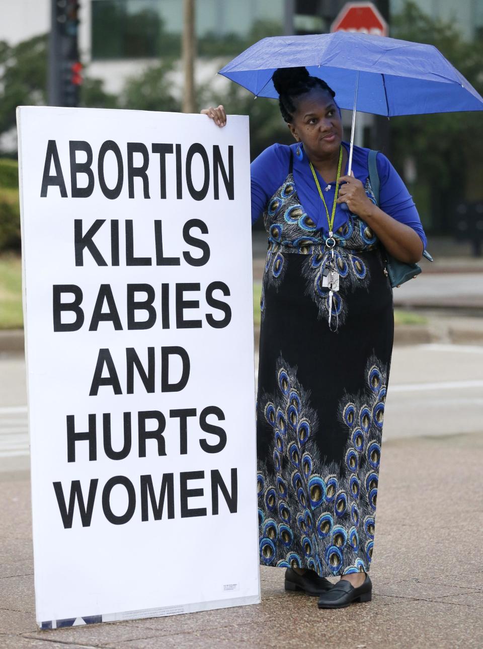 File-In this file photo made Monday, July 15, 2013, anti-abortion activist Teresa Steward of Desoto, Texas, stands on the curb sidewalk holding a sign in front of city hall as an abortions rights rally gets underway, in Dallas. A federal appeals court on Thursday March 27, 2014, upheld Texas' tough new abortion restrictions that shuttered many of the abortions clinics in the state. A panel of judges at the New Orleans-based 5th Circuit Court of Appeals overturned a lower court judge who said the rules violate the U.S. Constitution and served no medical purpose. In its opinion, the appeals court said the law "on its face does not impose an undue burden on the life and health of a woman." (AP Photo/Tony Gutierrez)