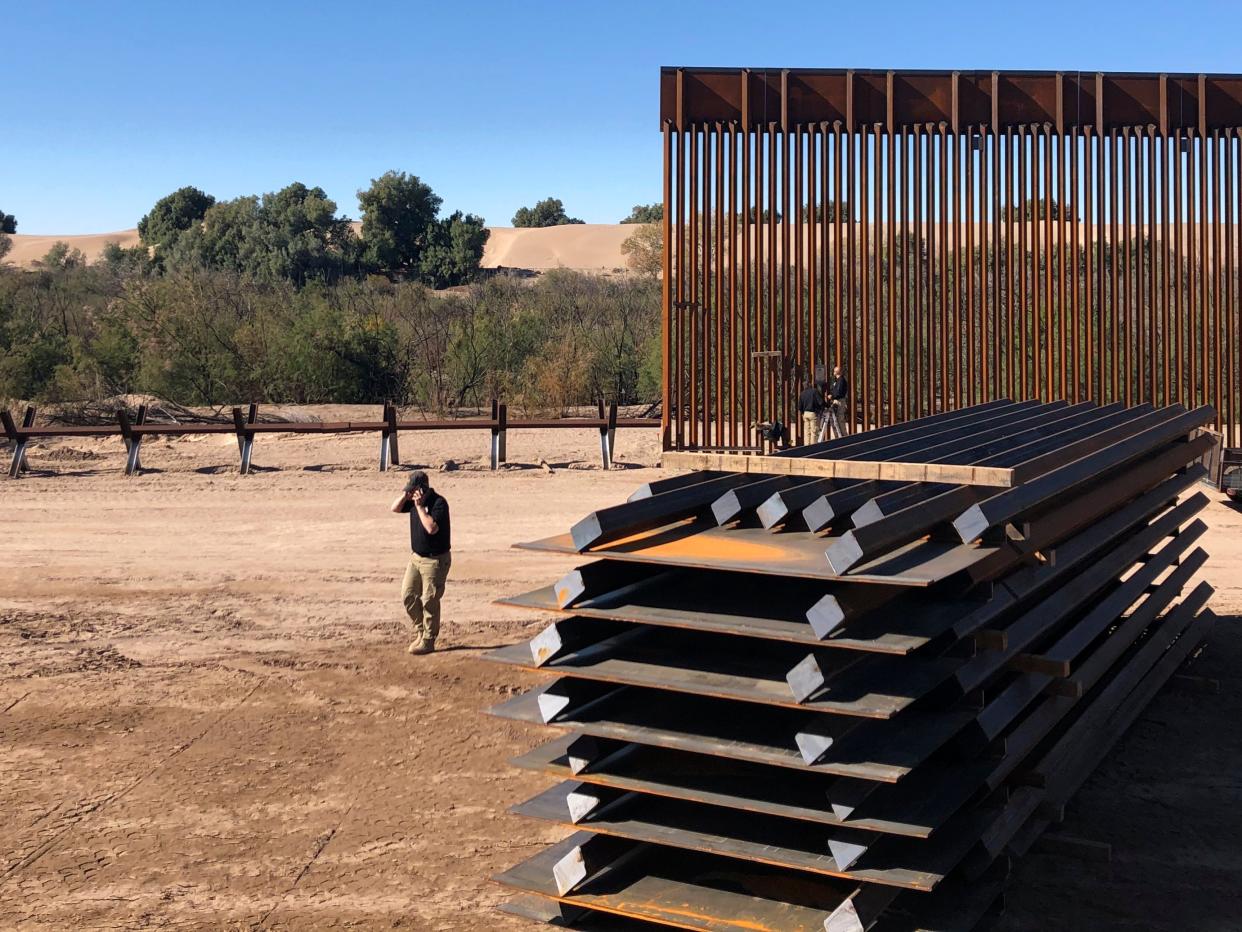 A man passes new border wall sections, right, as they replace the old fencing, left, Friday, Jan. 10, 2020, near Yuma, Arizona (AP)