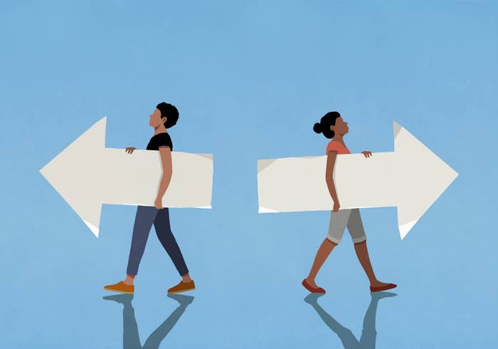 Two people, facing away from each other, are each carrying large arrows pointing in opposite directions