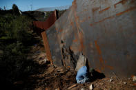 A migrant, who is part of a caravan of thousands from Central America trying to reach the United States, looks at a hole under the border wall in Tijuana, Mexico, December 7, 2018. REUTERS/Carlos Garcia Rawlins