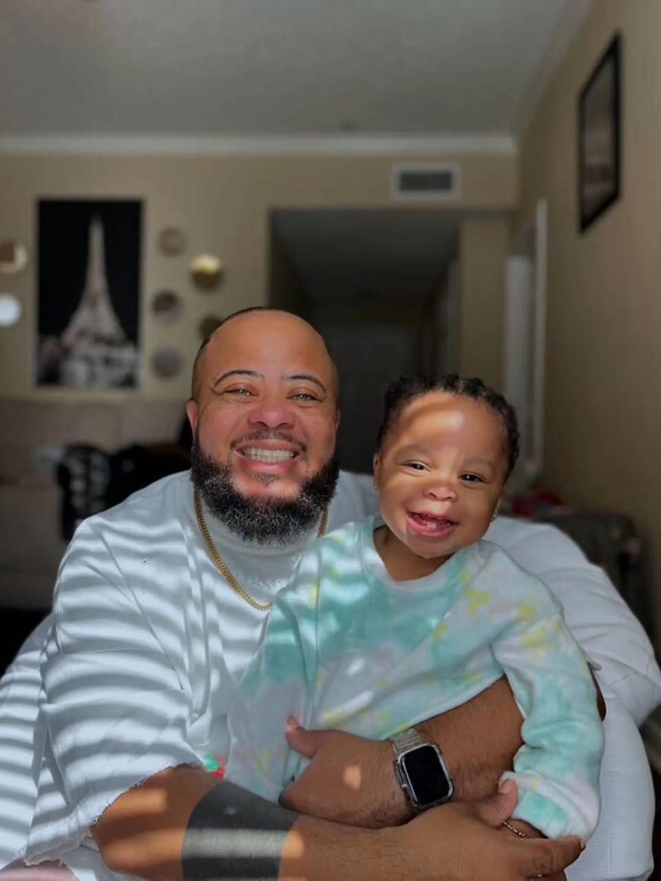 Coleman holds his daughter at home as they both smile.