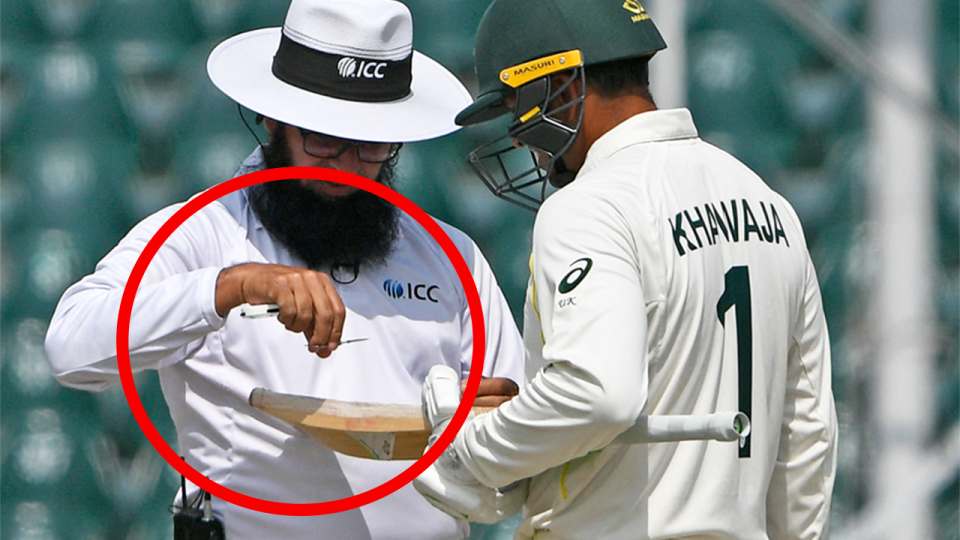 Usman Khawaja (pictured right) gets hit bat attended to by the umpire.