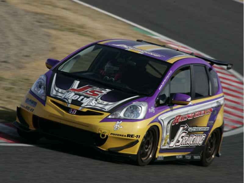 a honda fit race car driving on a track