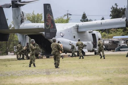 Japan Self-Defense Force soldiers carry aid materials for those affected by multiple large-scale earthquakes in Kumamoto region from a U.S. military Osprey aircraft at Hakusui sports park in Minamiaso town, Kumamoto prefecture, southern Japan, in this handout photo taken on April 18, 2016 and released by U.S. Marine Corps. REUTERS/Cpl. Nathan Wicks/U.S. Marine Corps/Handout via Reuters