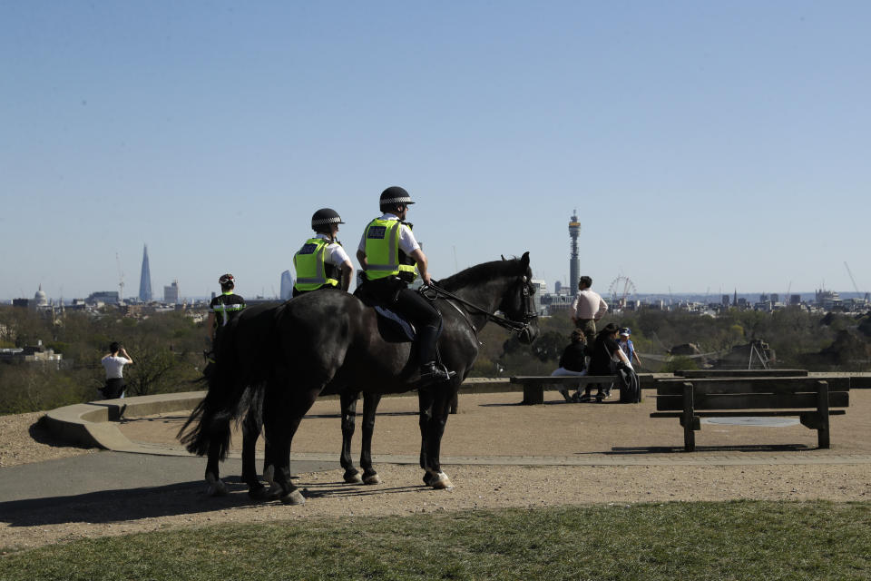 Mounted police on horseback stand on the top of Primrose Hill as they prepare to disperse people, to stop the spread of coronavirus and keep the park open for people observing the British government's guidance of social distancing, only using parks for dog walking, one form of exercise a day, like a run, walk, or cycle alone or with members of the same household, in London Sunday, April 5, 2020. The new coronavirus causes mild or moderate symptoms for most people, but for some, especially older adults and people with existing health problems, it can cause more severe illness or death. (AP Photo/Matt Dunham)