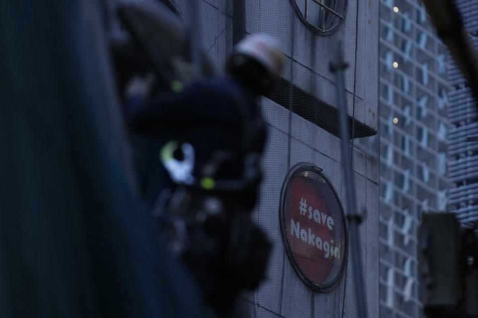 Men work at the site of the Nakagin Capsule Tower, a capsule hotel n the Ginza district, as parts of the hotel were being demolished, in Tokyo on April 7, 2022. It’s now being demolished in a careful process that includes preserving some of its 140 capsules, to be shipped to museums around the world. A poster that reads, "#save Nakagin," pasted on one of the hotel windows. (AP Photo/Hiro Komae)