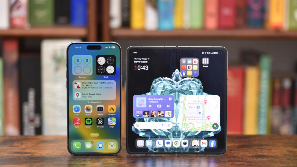 OnePlus Open standing up next to an iPhone 15 Pro Max