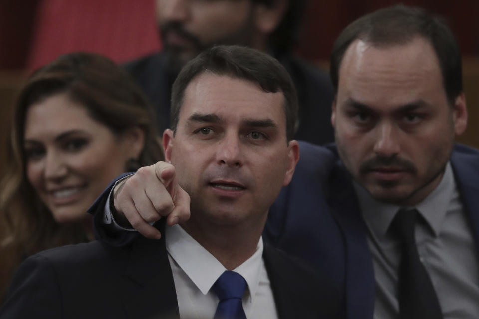 FILE - Flavio Bosonaro, center, and Carlos Bolsonaro, sons of Brazil's President-elect Jair Bolsonaro, attend a ceremony officially confirming the presidential elections results which their dad won at the Supreme Electoral Court in Brasilia Brazil, Dec. 10, 2018. Brazil's federal police carried out a search warrant Jan. 29, 2024 for Carlos Bolsonaro, a Rio de Janeiro city councilman, an officer with knowledge of the operation told The Associated Press. (AP Photo/Eraldo Peres, File)