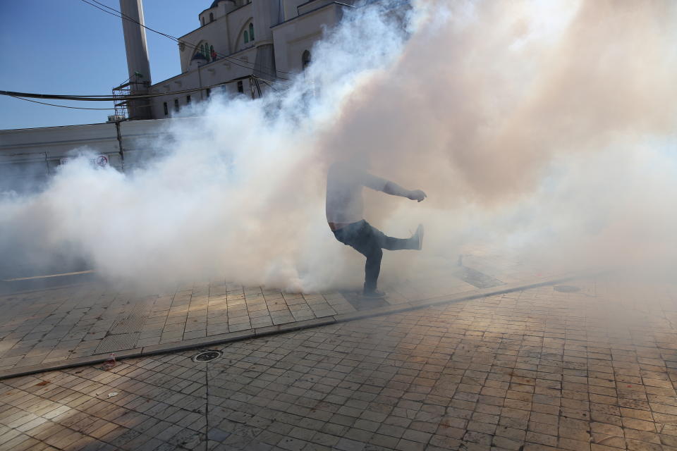 Protesters hit back tear gas canisters thrown by police, as thousands of opposition supporters protest in Tirana, Albania on Saturday, March 16, 2019. Albanian opposition supporters clashed with police while trying to storm the parliament building Saturday in a protest against the government which they accuse of being corrupt and linked to organized crime.(AP Photo/Visar Kryeziu)